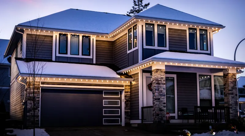 Two-story home at night with a continuous line of warm white C9 lights along every roofline, installed by Trent Delgadillo